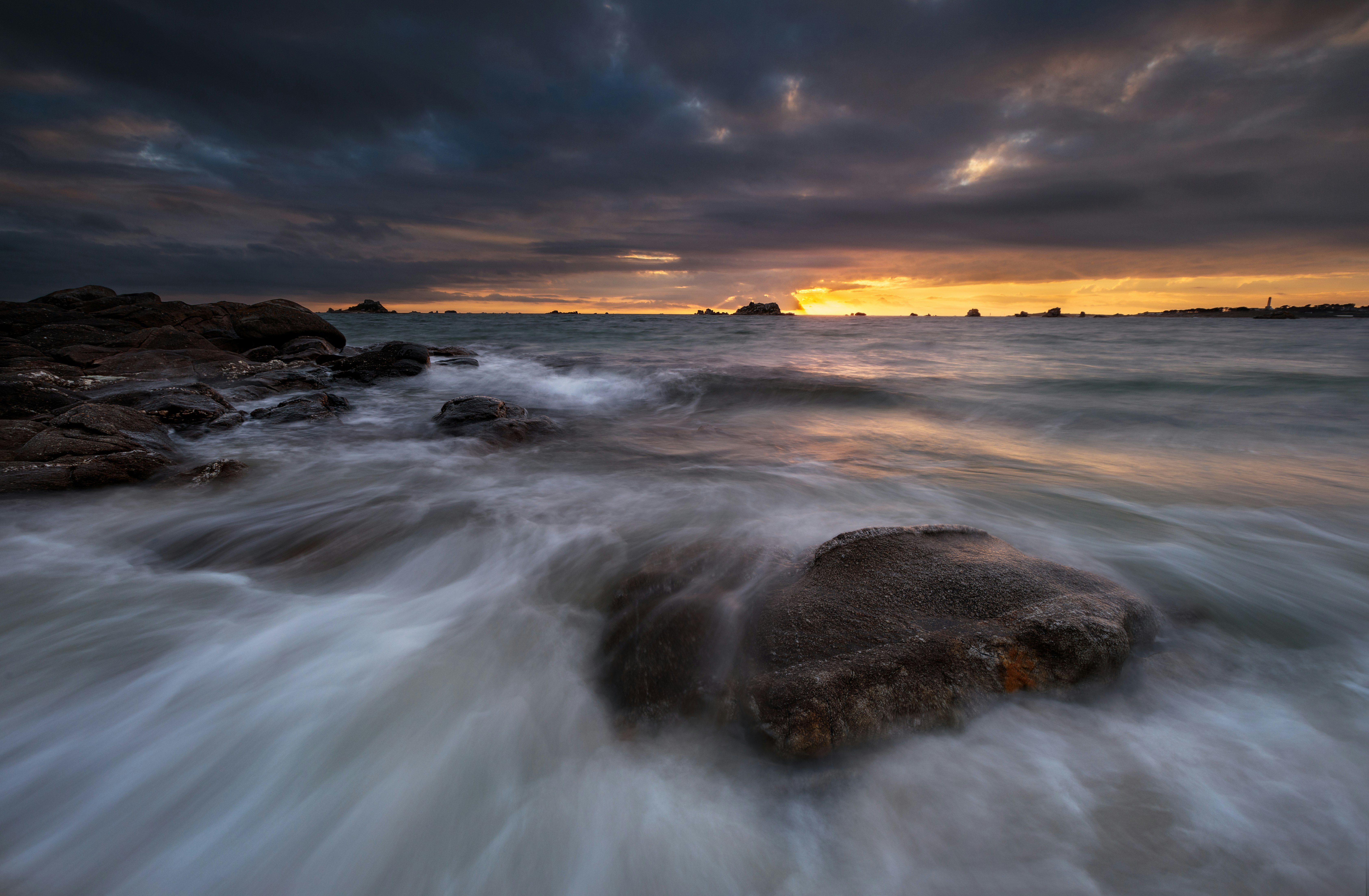 ocean waves crashing on shore during sunset